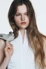 Vestido midi blanco, con cuello halter y falda con terminación en godets, lo que le da volumen y movimiento.