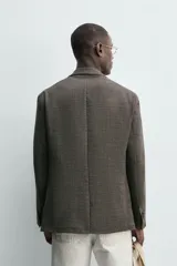 Blazer regular fit confeccionado en mezcla de lana y lino, con diseño de pata de gallo en tonos marrones y grises. Cuenta con cuello de solapas de muesca, cierre frontal de dos botones, bolsillos de plastrón en la cadera y bolsillo de vivo en el pecho.