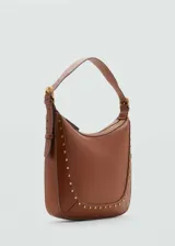 Bolso de hombro color marrón con diseño estructurado, cierre de cremallera superior y detalle de tachuelas metálicas doradas en el contorno frontal. Cuenta con un asa ajustable con hebilla.