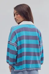Remera tipo polo de algodón, de calce oversize, con diseño a rayas en tonos azul y celeste, cuello clásico blanco, botonadura corta, hombros caídos y mangas cortas.
