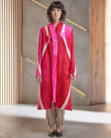 Tapado largo de lana merino afieltrada, color fucsia con diseño tie-dye artesanal en tonos claros y crudos. Tiene cuello que se prolonga a modo de cinto, aberturas laterales y bolsillos.