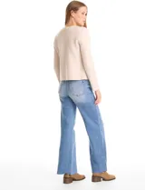 Chaqueta de punto color beige, con cuello redondo, cierre frontal mediante botones metálicos y bolsillos aplicados en la parte delantera.