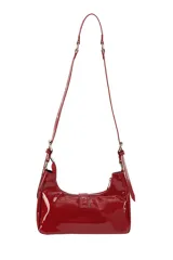 Bandolera de charol color rojo, con diseño estilo baguette. Presenta cierre superior, correas ajustables con hebillas metálicas y detalles decorativos de hebillas en la parte frontal.