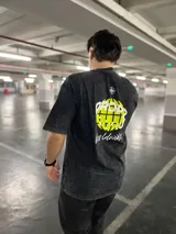 Remera negra con efecto washed, con estampado trasero de un globo terráqueo en verde vibrante y la palabra "Dropz" en blanco. Debajo, la palabra "Worldwide" en tipografía script blanca y un símbolo de brújula en la parte superior.