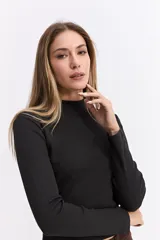 Polera de manga larga con cuello alto, confeccionada en tejido de algodón con textura acanalada y calce ajustado al cuerpo.