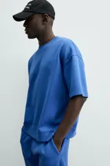 Sudadera de manga corta color marrón oscuro, con cuello redondo y bajo acabado en rib. Presenta un corte relajado y holgado (boxy fit).