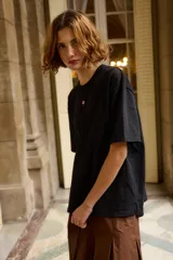 Remera de algodón color negro, de corte holgado y manga corta, con un pequeño detalle bordado en el centro del pecho.