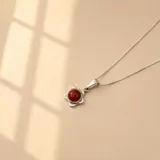 Collar de plata 925 con cadena fina y dije en forma de flor con centro de resina color rojo.