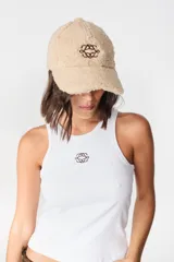 Gorro tipo baseball de tela tipo peluche color crudo, con bordado central en color marrón.