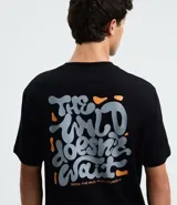 Remera negra de algodón con estampado psicodélico y lettering "The Wild Doesn't Wait" en el frente y la espalda. Diseño de corte comfort, cuello redondo y manga corta.