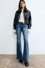 Pantalón jean acampanado de tiro bajo en denim levemente elástico, con bolsillos delanteros decorativos, bolsillo monedero y bolsillos abiertos atrás.