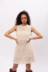 Vestido corto color crema, tejido a crochet con lurex, sin mangas y cuello redondo.