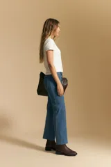 Jean de corte recto y tiro medio, confeccionado en denim elastizado de color negro. Presenta un diseño clásico con cierre de botón y cremallera, bolsillos laterales y traseros, y ruedo con terminación deshilachada.