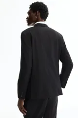 Blazer negro de corte entallado, confeccionado en tejido suave con solapas de muesca finas, un botón de cierre frontal, bolsillos con solapa y bolsillo superior en el pecho.
