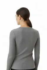 Polera de punto canalé color gris, de manga larga, cuello redondo a la base y corte ajustado al cuerpo.