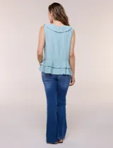Blusa blanca sin mangas confeccionada en tejido de satén con suave textura arrugada y caída fluida. Cuenta con escote en V con volante en el cuello y ruedo estilo peplum con doble capa de volados superpuestos.