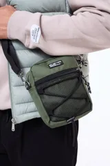 Morral de estilo urbano color verde militar, con compartimento principal con cierre, bolsillo frontal de malla con cordón elástico ajustable y correa de hombro regulable.