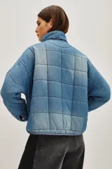 Campera acolchada de corte holgado con diseño de costuras cuadradas, cierre frontal con cremallera y cuello alto. Presenta un acabado lavado en tonos gris y negro.