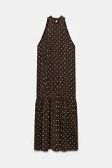 Vestido midi de cuello halter y hombros descubiertos, confeccionado en tejido con lyocell. Presenta un diseño de lunares claros sobre fondo oscuro y bajo acabado en volante.