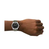 Reloj analógico Emporio Armani con caja de acero inoxidable plateada, esfera negra con subesferas de cronógrafo y correa de cuero en color verde oliva.