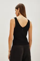 Musculosa de punto color negro con escote en V y detalle de pequeñas aplicaciones brillantes en toda la prenda.