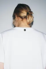 Camiseta blanca de algodón, corte regular, cuello redondo y manga corta, con bolsillo cuadrado de tejido efecto piel color camel en el pecho.