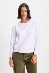 Remera de manga larga color blanco, con cuello redondo y corte holgado. Presenta un pequeño bordado en el centro del pecho.