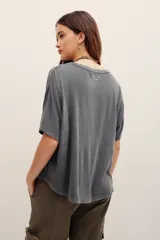 Remera de manga corta color gris oscuro con efecto desgastado, escote redondo amplio y corte holgado.