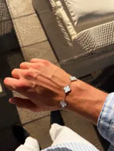 Pulsera de acero con cadena de eslabones y cinco dijes en forma de trébol con incrustaciones de nácar blanco.