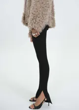 Leggings negros de corte entallado con aberturas en el bajo y detalle de puntilla en la cintura. Cuentan con cierre lateral invisible.