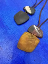 Collar de largo regulable con cordón de cuero y dos piezas colgantes de resina en tonos tierra y marmolados.