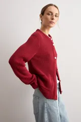 Chaqueta tejida de punto acanalado en color azul marino, con cuello redondo, cierre frontal de botones metálicos y dos bolsillos delanteros aplicados.