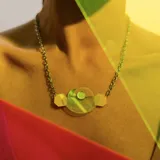 Collar con cadena dorada y dije de acrílico amarillo y verde con formas geométricas.