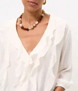 Blusa tipo bata de viscosa color blanco crudo, con cuello en V, volados frontales y mangas largas con puños elásticos. Confeccionada en tejido con textura crinkle de la marca Marfinno.