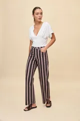 Jean barrel de tiro alto con silueta amplia y piernas ligeramente curvas que se afinan hacia el tobillo. Diseño con estampa de rayas verticales, bolsillos delanteros y traseros, cierre con botón y cremallera.