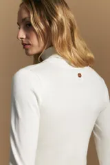 Polera de tejido fino color negro, con cuello alto y mangas largas con terminación sutilmente fruncida. Diseño ajustado al cuerpo.