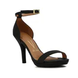 Sandalia de tacón alto negra, con plataforma delantera y una tira ancha sobre los dedos. Posee una tira fina alrededor del tobillo con hebilla metálica dorada para ajuste.