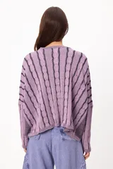Sweater de punto con diseño de rayas verticales en relieve y textura trenzada, color terracota y beige. Presenta cuello redondo, corte holgado y diseño cropped.