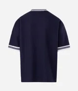 Remera de tejido texturizado color azul marino, con cuello redondo y mangas cortas con puños a rayas blancas. Presenta bordados frontales con la inscripción 'Future Co.', el número '98', un logo ovalado y estrellas.