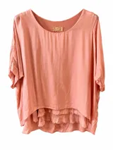 Blusa holgada de seda color coral, con diseño de doble capa y detalles de flecos en el borde inferior. Cuenta con mangas cortas amplias y cuello redondo.