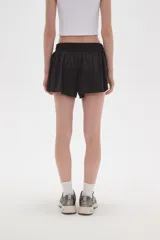 Short de poliéster color celeste, de calce holgado y tiro alto, con cintura elástica ajustable mediante cordón y bolsillos laterales.
