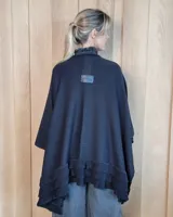 Ruana tejida de algodón con diseño abierto, terminaciones con volados y textura acanalada en los bordes.