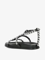 Sandalias planas color blanco con tiras decoradas con tachas plateadas y cierre de velcro.