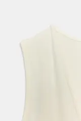 Body entallado color marrón oscuro con escote pronunciado en pico y manga sisa. Cierre en la parte inferior con botones a presión.