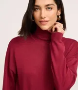 Vestido de punto negro, de manga larga y cuello alto, con corte recto y largo midi.