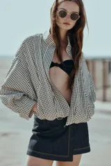 Chaqueta estilo bomber con estampado de cuadros vichy en blanco y negro, de cuello subido, manga larga y bolsillos delanteros de vivo. Cuenta con bajo abullonado y cierre frontal con cremallera oculta.