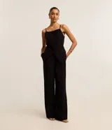 Pantalón de vestir negro, corte pantalona ancho y fluido, con pliegues frontales y cierre de botón en la cintura.