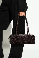 Cartera de cuero vacuno tipo baguette, de color gris claro con acabado vintage y diseño alargado. Cuenta con dos asas largas para llevar al hombro, cierre superior y el logo de la marca grabado en el frente.