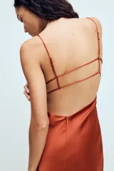 Vestido midi de tejido satinado color terracota, con escote en pico, tirantes finos ajustables y espalda con tiras cruzadas.