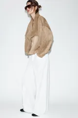 Chaqueta de efecto ante con cuello solapa envolvente, manga larga con hombro caído y bajo con elástico interior. Cuenta con bolsillos laterales ocultos en costura y forro interior.